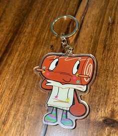 a keychain with a cartoon character on it sitting on a wooden table next to a cell phone