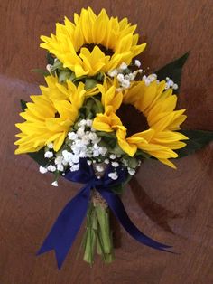 sunflowers and baby's breath tied together in a blue ribbon on a wooden table