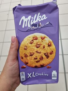 a person holding up a bag of milka cookies with almonds on it's side