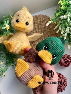 two crocheted stuffed birds sitting next to each other in front of some flowers