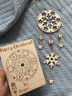 a wooden christmas ornament next to a book on a blue blanket with other ornaments