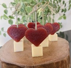 four pieces of cheese with hearts on them sitting on top of a piece of wood