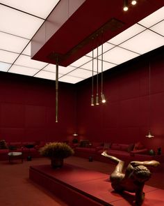 a living room with red walls and couches in the center, lights hanging from the ceiling