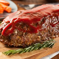 a piece of meat covered in ketchup sitting on top of a wooden cutting board