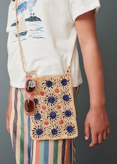 a woman carrying a straw bag with sunglasses on it