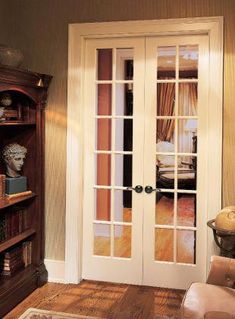 a living room filled with furniture next to a book shelf and door leading to a bedroom