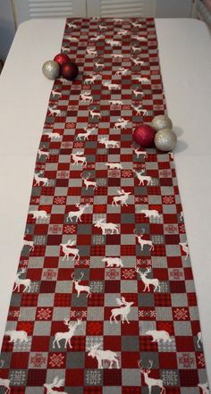 the table is decorated with red and gray plaid fabric, silver balls and ornaments on it