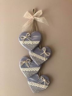 three heart shaped ceramic ornaments hanging on a wall with a ribbon tied to it's side