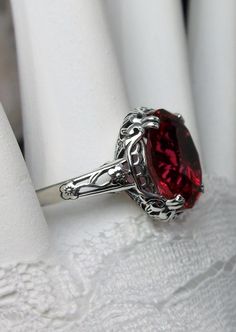 Simulated Ruby Edward Design#70 (smaller version) Custom Made Here we have an Edwardian reproduction ring in sterling silver filigree with a 5ct Red/Pink simulated ruby gemstone solitaire. The faceted oval gemstone gem is 12mm in length and 10mm in width. This ring also sits 7mm off the finger. The inside of the band is marked 925 for solid sterling. Notice the beautiful leaf design of the silver filigree setting and etched band. This is a lovely rendition of an Antique filigree ring; and it is Engraved Silver Ruby Ring For Anniversary, Victorian Style Silver Ruby Ring For Anniversary, Vintage Sterling Silver Ruby Ring For Collectors, Engraved Sterling Silver Ruby Ring For Wedding, Victorian Sterling Silver Ruby Ring For Gift, Antique Sterling Silver Ruby Ring For Anniversary, Antique Oval Ruby Ring In Sterling Silver, Collectible Oval Ruby Ring In Silver, Antique Sterling Silver Ruby Wedding Ring