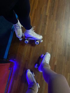 two people riding roller skates on top of a hard wood floored floor next to each other