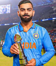 a man with a beard holding a trophy in his right hand and looking at the camera