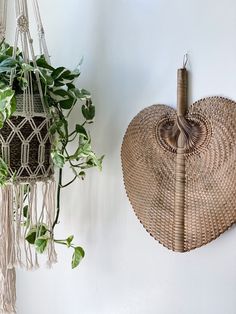 a plant hanging from the side of a wall next to a woven heart shaped pot holder