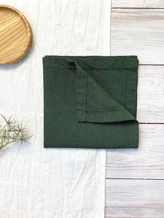 the folded napkin is next to a wooden bowl and spoon on a white tablecloth