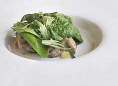 a white plate topped with greens and meat