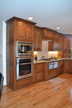 a large kitchen with wooden floors and stainless steel appliances on the counter top, along with hardwood flooring