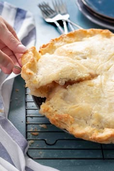 a person holding a piece of pie on top of a cooling rack