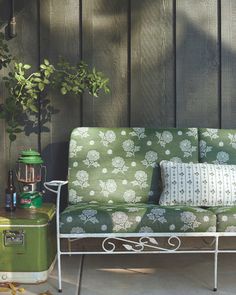 a green couch sitting on top of a wooden floor next to a metal table and lamp