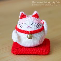 a small crocheted cat sitting on top of a red mat