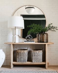 a mirror sitting on top of a wooden table next to two baskets filled with plants