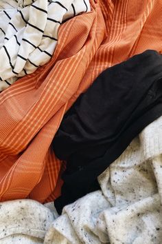 an orange and white shirt laying on top of a pile of clothes