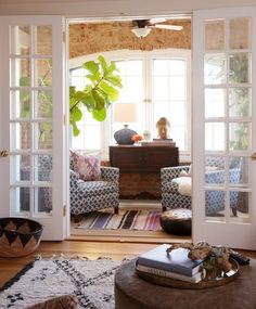 a living room filled with furniture and lots of doors open to the outside patio area