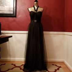 a dress on display in front of a red wall with a black mannequin