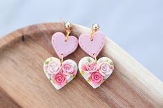 two heart shaped earrings with pink flowers on them