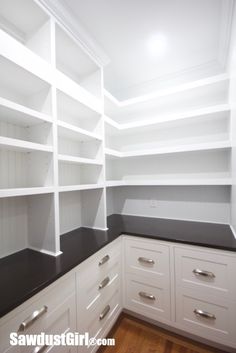 an empty pantry with white cabinets and black counter tops in a home remodeling project