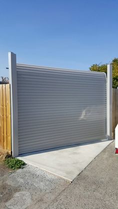 a closed garage door in front of a wooden fence