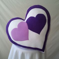 two heart shaped pillows sitting on top of a white table cloth covered headbands