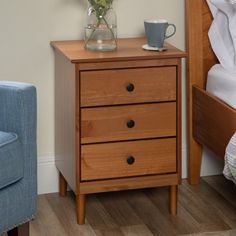 a wooden nightstand with two drawers next to a blue chair