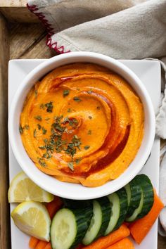 roasted red pepper hummus oil - free dip in a white bowl with sliced cucumbers