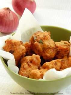 some food is in a green bowl on a white table cloth with an onion wedge