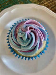 a cupcake with blue and pink frosting on a white plate