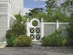 a white gate surrounded by bushes and trees