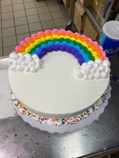 a rainbow cake with white frosting and sprinkles on the bottom is ready to be cut