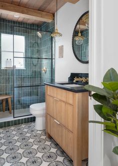 a bathroom with green tile and wood accents