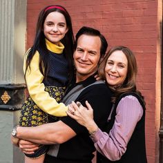 a man and woman hugging each other in front of a brick wall