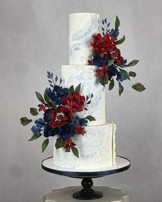 a three tiered wedding cake with red, white and blue flowers