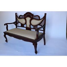 an antique wooden bench with upholstered seat and back cushions, on a white background