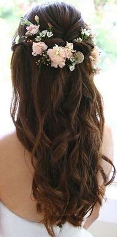 the back of a woman's head with flowers in her hair, looking out a window