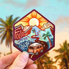 a hand holding up a sticker with the words follow the sun and an rv