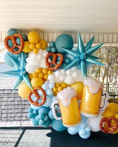 beer mugs and pretzels are on display in front of a balloon arch