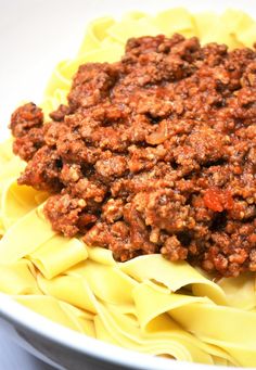 a bowl filled with pasta and meat sauce on top of it's own noodles