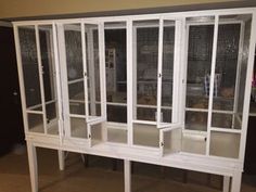 a large white cabinet with glass doors and shelves