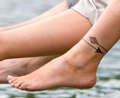 black and white photo of two people's legs with tattoos on them, one has an arrow