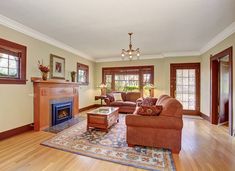 a living room filled with furniture and a fire place in the middle of a wooden floor