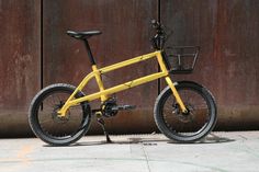 a yellow bicycle parked in front of a wooden wall