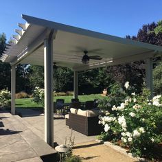 a covered patio with furniture and flowers in the foreground