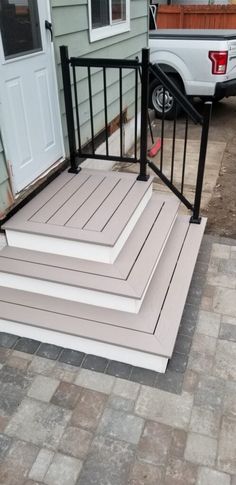 three steps leading to the front door of a house with a truck in the background